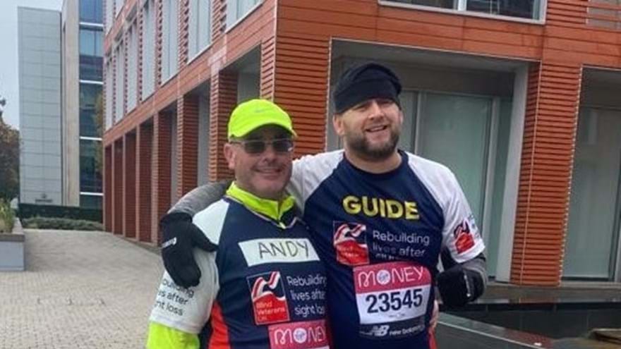 Blind veteran Andy and his guide, smiling, wearing Blind Veterans UK running tops