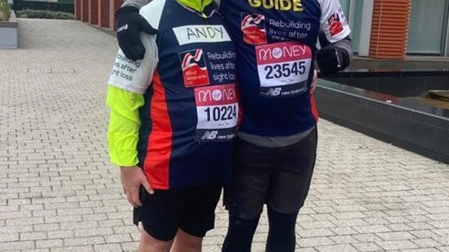 Blind veteran Andy and his guide, smiling, wearing Blind Veterans UK running tops