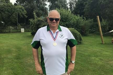 Blind veteran Steve standing with his hands on his hips, proudly wearing a national bowls medal