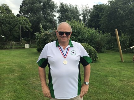 Blind veteran Steve standing with his hands on his hips, proudly wearing a national bowls medal