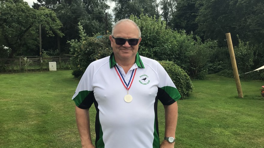 Blind veteran Steve standing with his hands on his hips, proudly wearing a national bowls medal