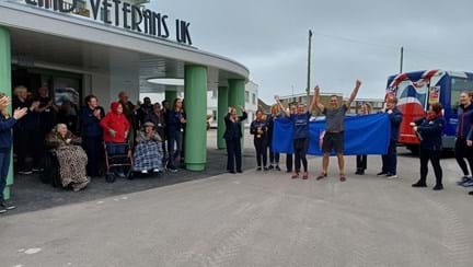 Lynn and Chris standing at the front of the Rustington Centre with their arms in the air. They are surrounded by staff and residents