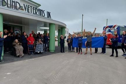Lynn and Chris standing at the front of the Rustington Centre with their arms in the air. They are surrounded by staff and residents