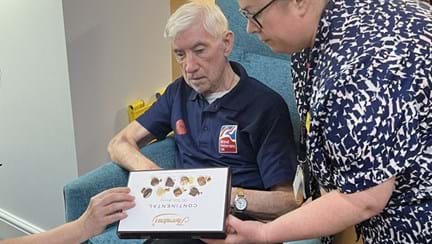 A blind veteran being offered a box of chocolates by centre staff