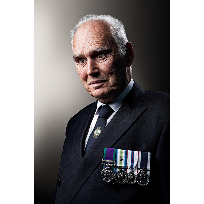 Blind veteran Terry wearing a navy jacket, tie, and medals