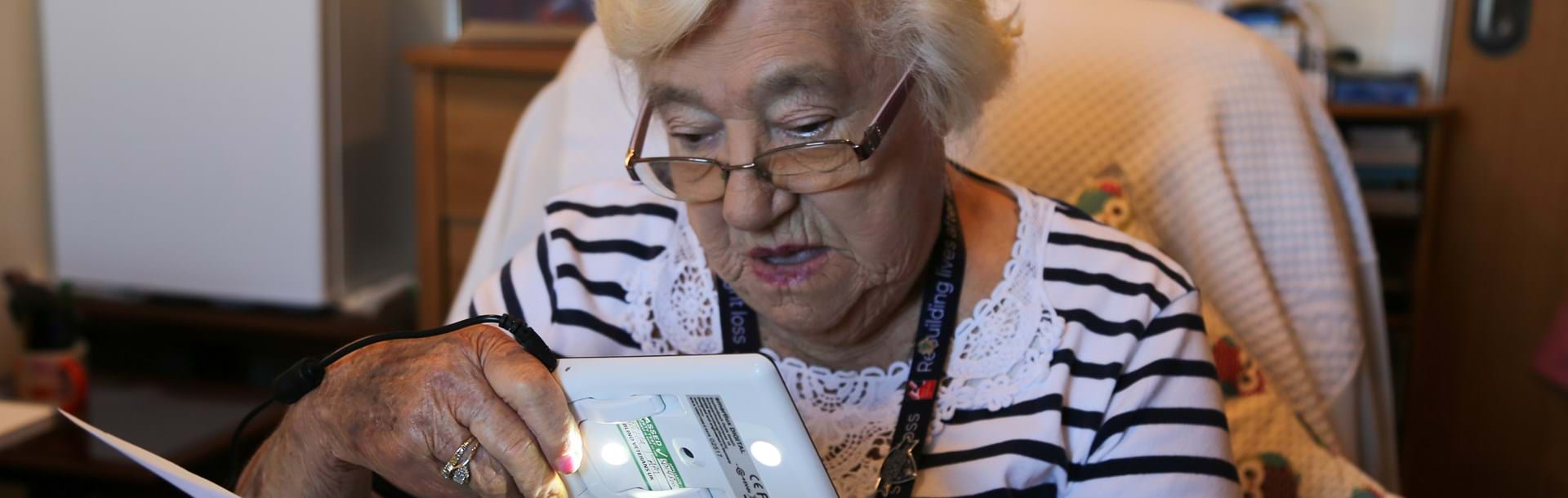 Blind veteran Win holding a device which she is using to look at old photographs 