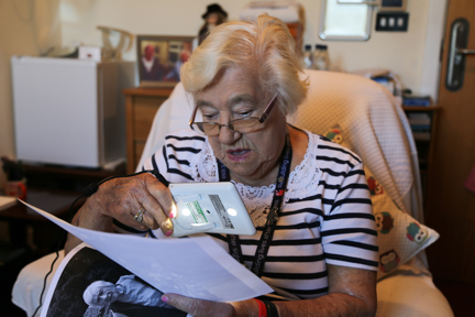 Blind veteran Win holding a device which she is using to look at old photographs