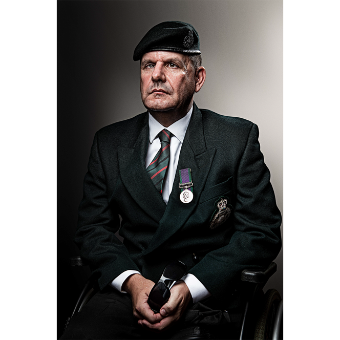 Blind veteran Steve wearing a green jacket, tie, beret, and medal