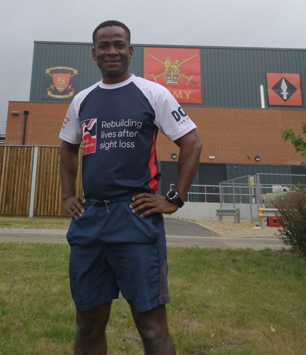 Adi stood in front of an Army building wearing his Blind Veterans UK t-shirt.