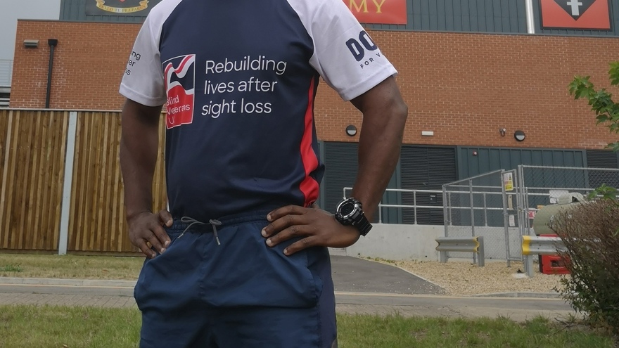 Adi stood in front of an Army building wearing his Blind Veterans UK t-shirt. 