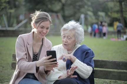 A photo of a cheerful senior and a carer using a smartphone together