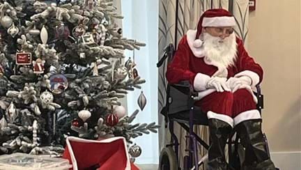 Father Christmas sits next to a Christmas tree at our Rustington centre