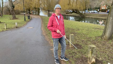 Blind veteran Mike walking through a park while holding a cane