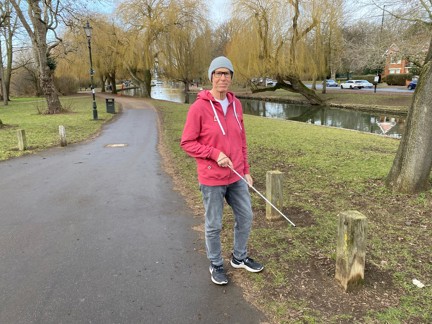 Blind veteran Mike walking through a park while holding a cane