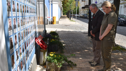 Nick Caplin, stood next to Major General Yulia Laputina, standing with heads bowed at the Borodyanka Memorial, where they stand in front of images of Ukrainian soldiers and memorial wreaths