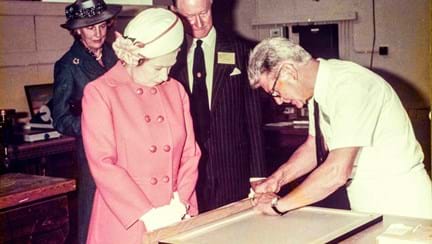 Her Majesty The Queen observing a blind veteran attaching a panel of wood to a frame