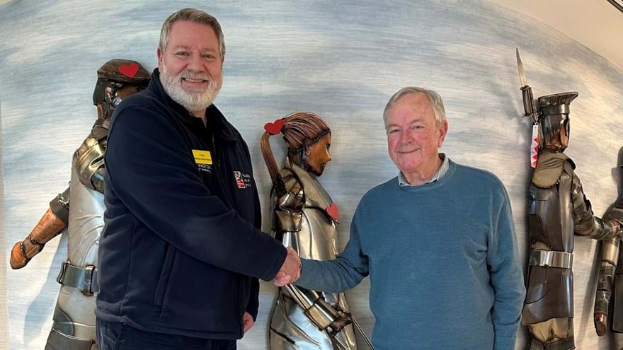 Member Jim visiting Rustington to make his donation shaking hands with a staff member in front of their statue