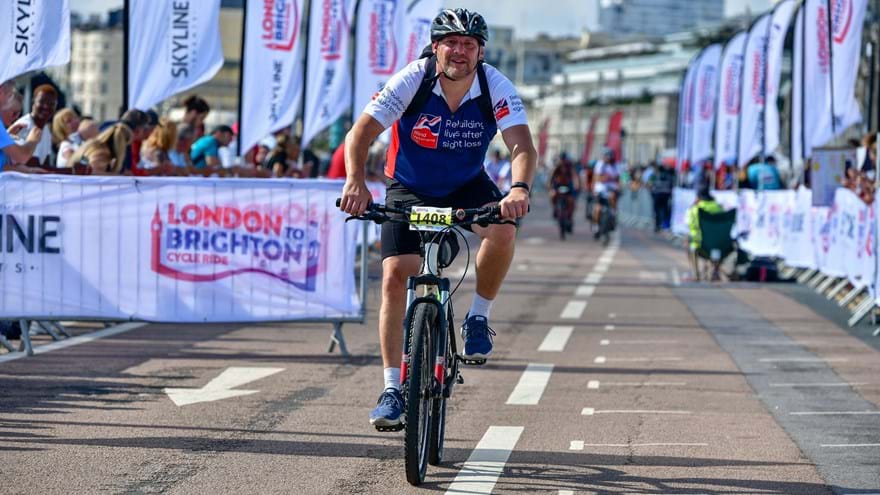 Gary on his bike, wearing a Blind Veterans UK training shirt, during the London to Brighton cycle