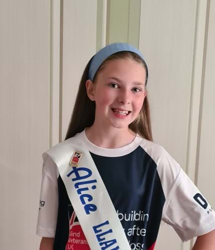 A photo of Emmie pictured wearing her Miss Alice sash over a Blind Veterans UK t-shirt
