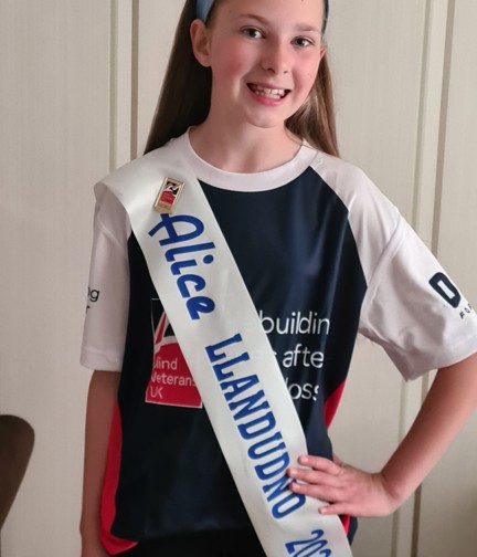 A photo of Emmie pictured wearing her Miss Alice sash over a Blind Veterans UK t-shirt