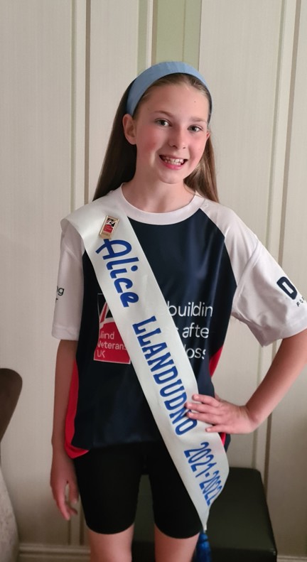 A photo of Emmie pictured wearing her Miss Alice sash over a Blind Veterans UK t-shirt