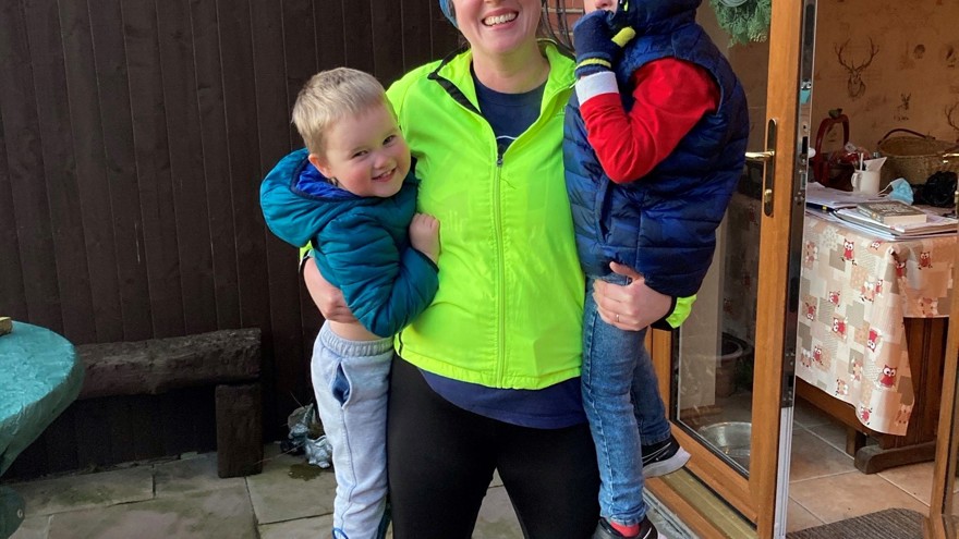 Charity supporter Sam, wearing running gear and holding up her two sons in her arms