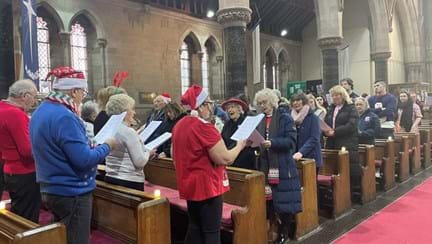 Blind veterans and staff in a church holding sheet music as they sing
