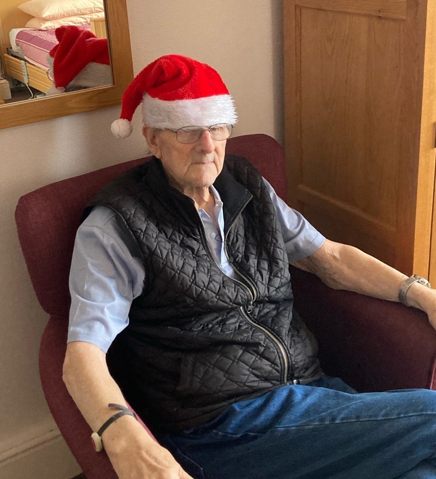 Blind veteran Harry sitting down, wearing a Christmas hat