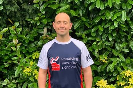 A photo of Justin Rookes, in running gear and a Blind Veterans UK top