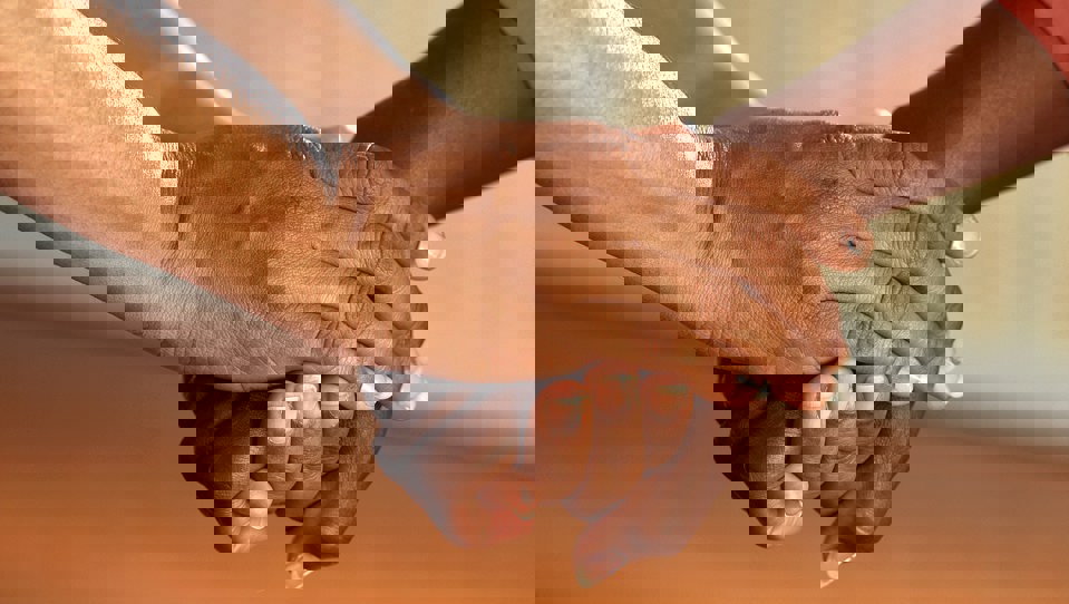A pair of hands holding another person's hand in a comforting way