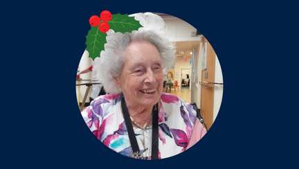 Blind veteran Rosalie wearing a Christmas hat, detailed with an illustration of holly.