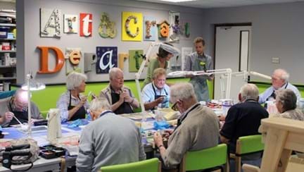 Blind veterans sitting at a long table, taking part in arts and crafts activities