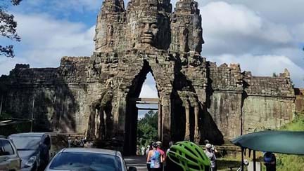 Group of cyclists stopped to admire and take pictures of large temple in Cambodia