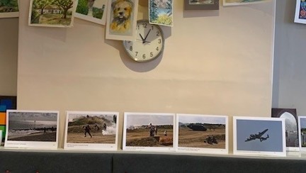 Some of Bob's watercolour paintings hanging up and Brian's photographs below resting against the wall