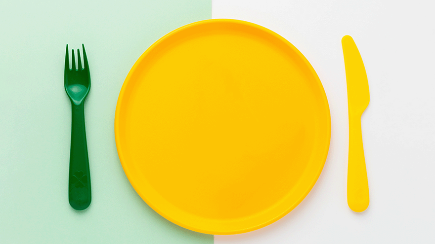 A plate, cutlery and placemat in bright, contrasting colours