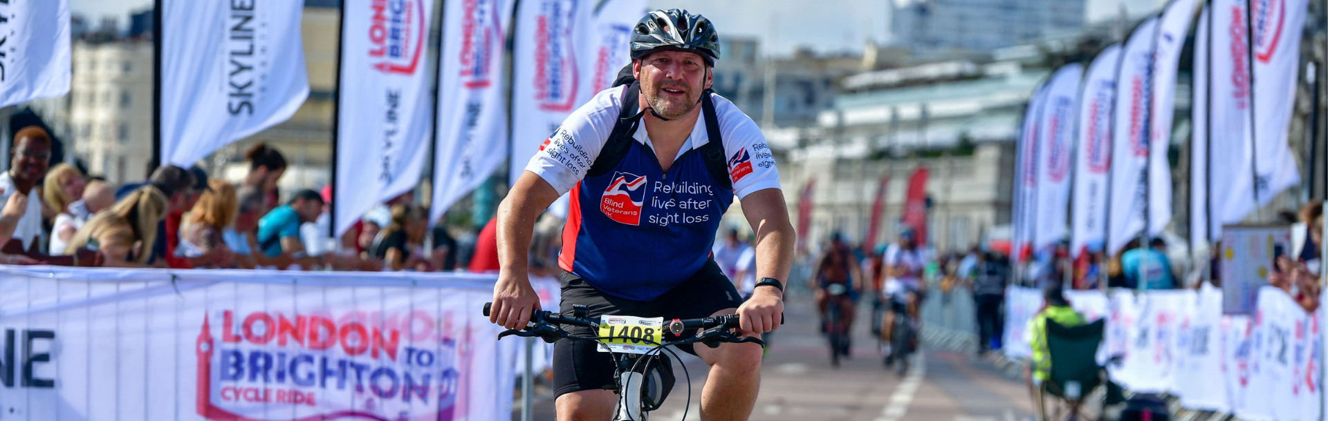 Supporter Gary on his bike, crossing the finish line of the race wearing a Blind Veterans UK T-shirt