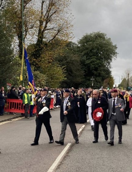 Alan holding the Blind Veterans UK Standard and walking beside blind veteran Jim