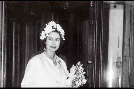 A black and white photograph of a young Queen Elizabeth, holding a bouquet of flowers