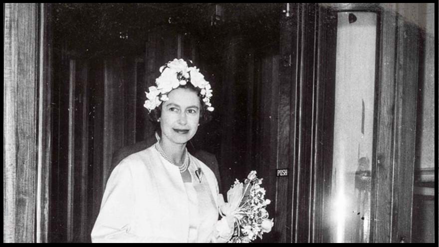 A black and white photograph of a young Queen Elizabeth, holding a bouquet of flowers