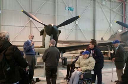 A group of blind veterans looking at a plane at Cosford