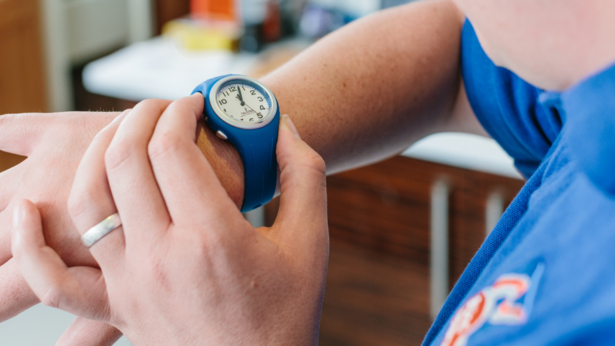 A close up of a blind veteran's wrist wearing a blue talking timer watch.