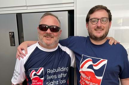 Chris and his son in Blind Veterans UK t-shirts with their arms around each others shoulders