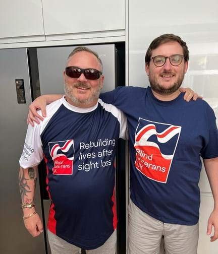 Chris and his son in Blind Veterans UK t-shirts with their arms around each others shoulders