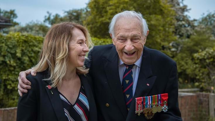 Blind veteran Ron wearing his military badges and laughing with care worker Kirsty