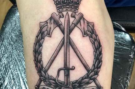 A close up photo of a tattoo of the Royal Pioneers cap badge on an arm