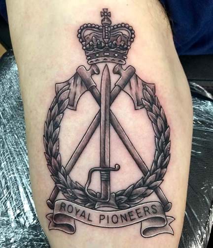 A close up photo of a tattoo of the Royal Pioneers cap badge on an arm