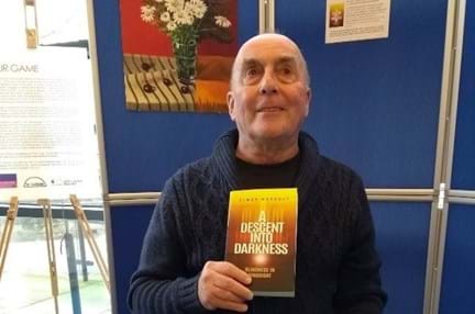Blind veteran, Simon, holding up a copy of his first book at the launch event