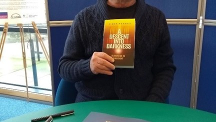 Blind veteran, Simon, holding up a copy of his first book at the launch event