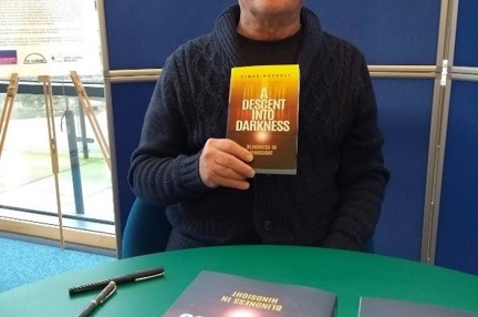 Blind veteran, Simon, holding up a copy of his first book at the launch event