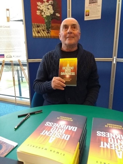 Blind veteran, Simon, holding up a copy of his first book at the launch event